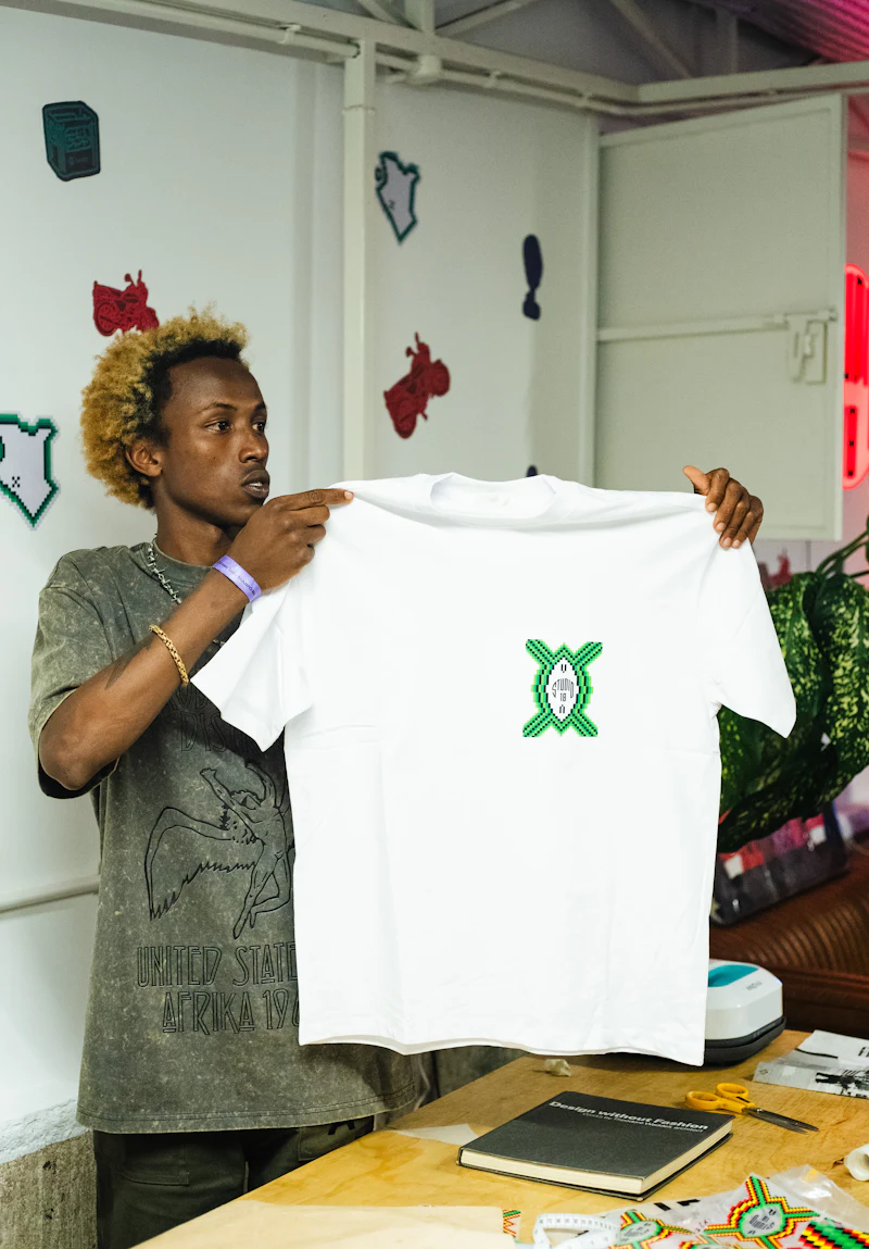 Man holding up a finished white t-shirt with a green printed emblem