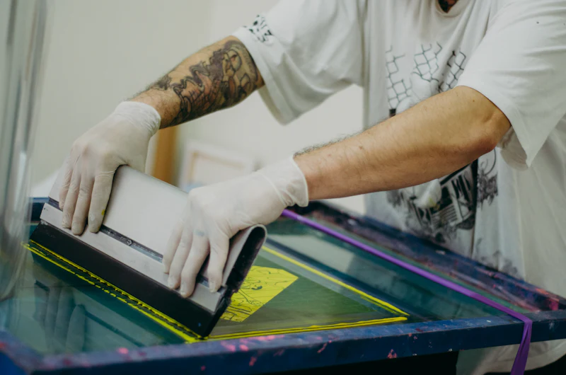 Gloved hands lining up a screen on a printing press