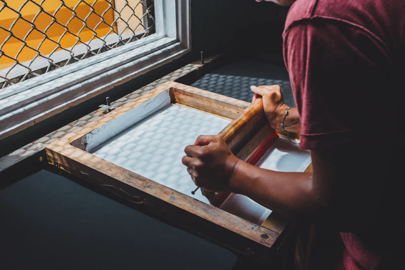 Printer holding a screen printing frame up to the light from a window